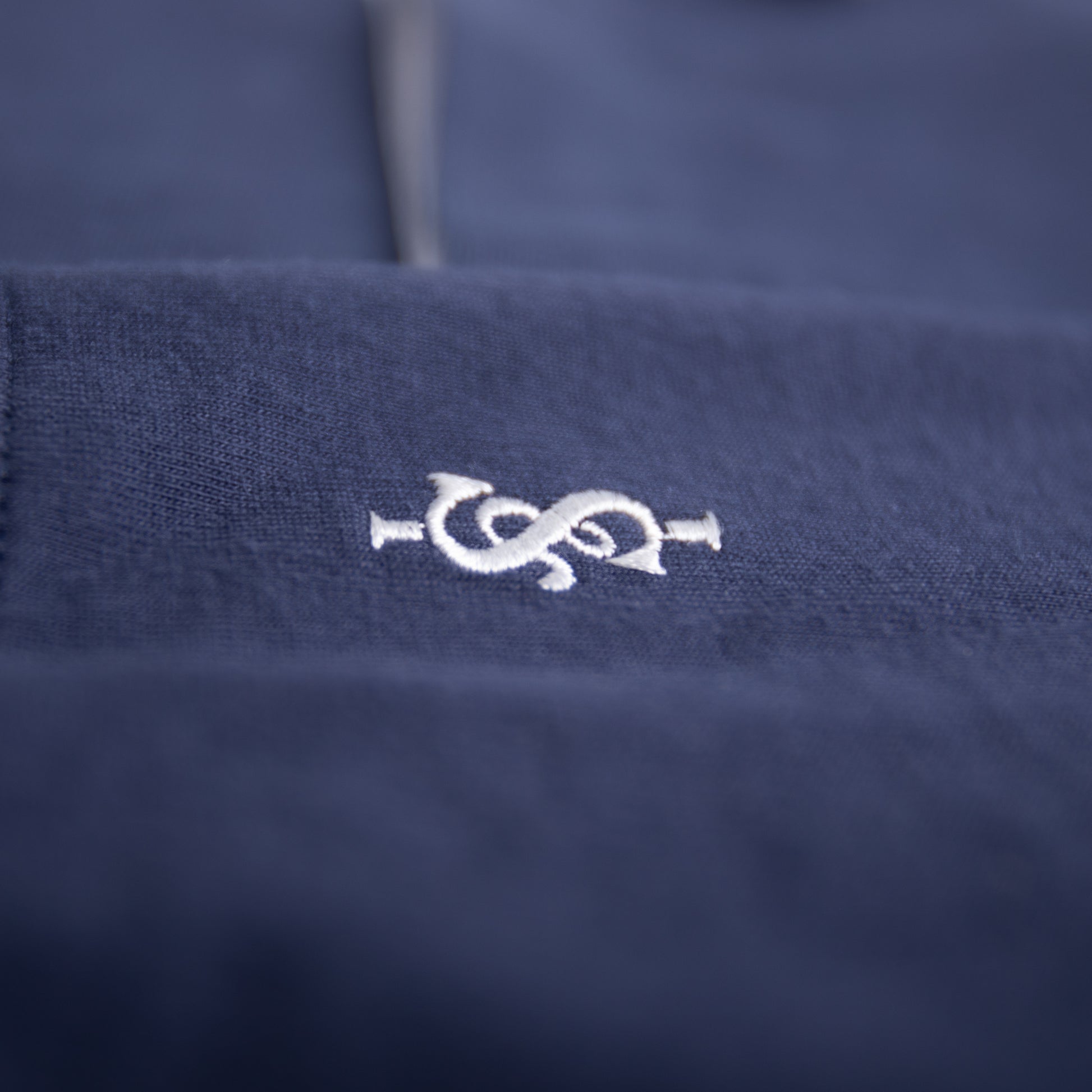 Navy blue fabric with a white embroidered logo on a blurred background